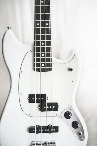 white and black electric bass guitar on white surface