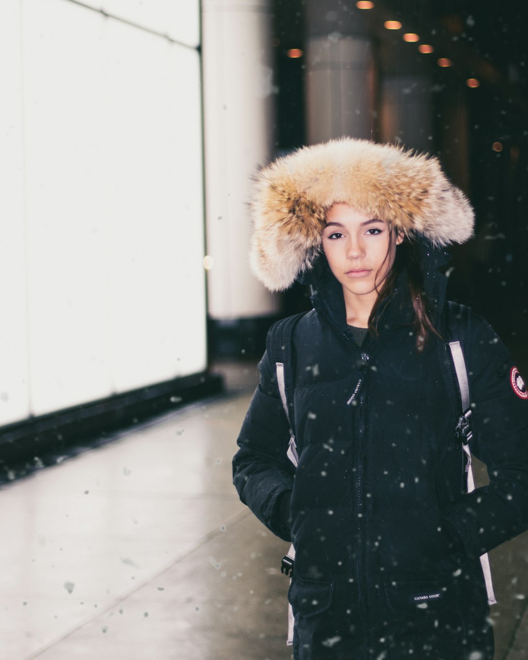 woman in black parka jacket standing while snowing