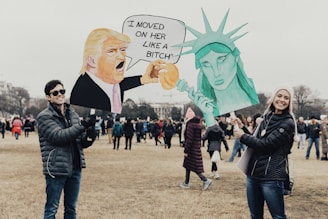 person wearing black bubble jacket holding donald trump signage