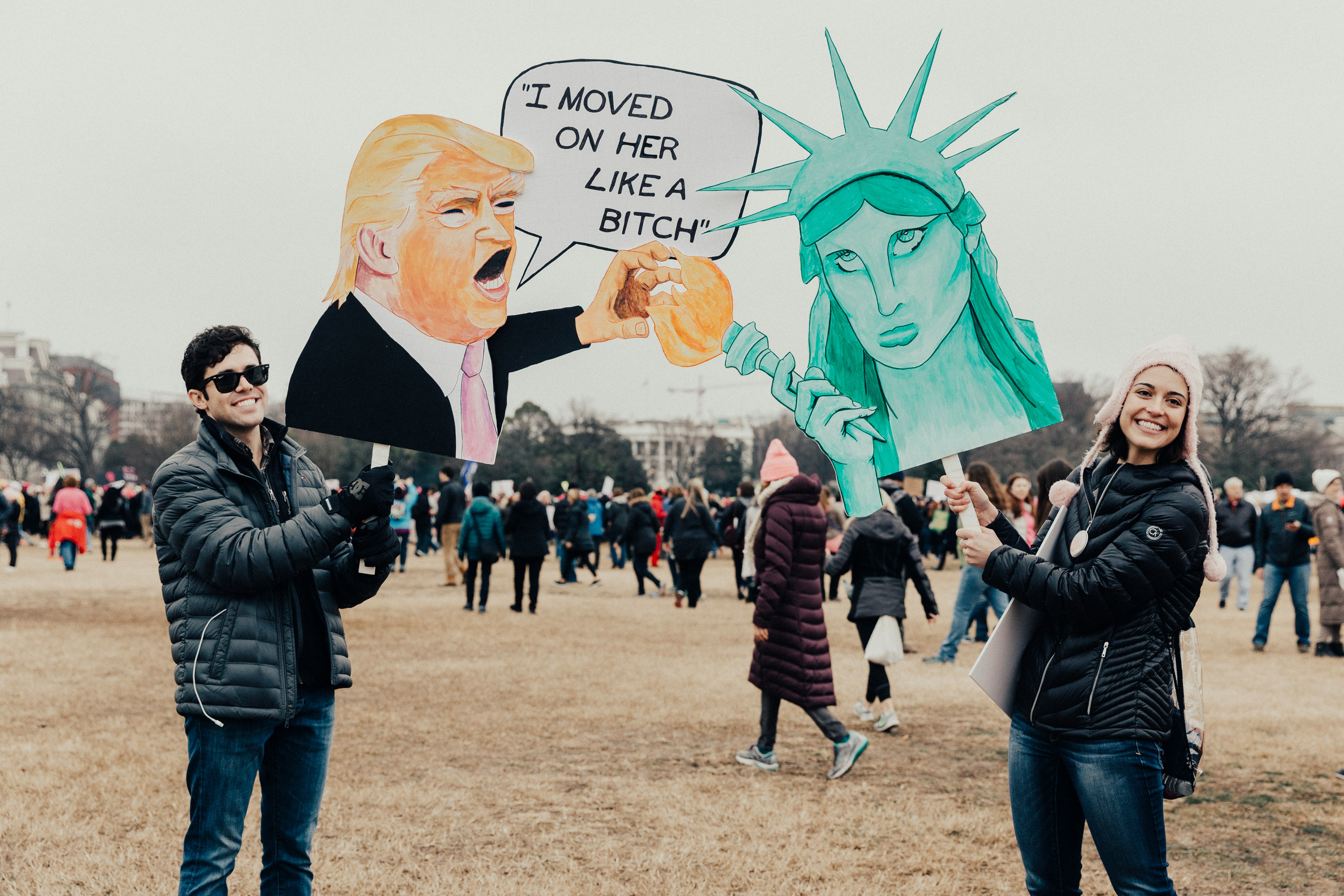 person wearing black bubble jacket holding donald trump signage