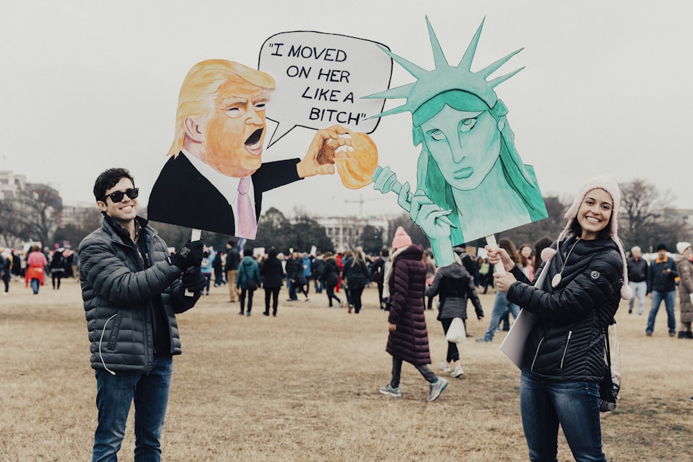 Personne portant une veste bulle noire tenant une pancarte Donald Trump