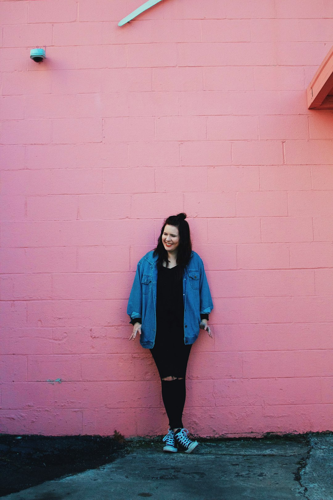 woman standing beside pink brick painted wall