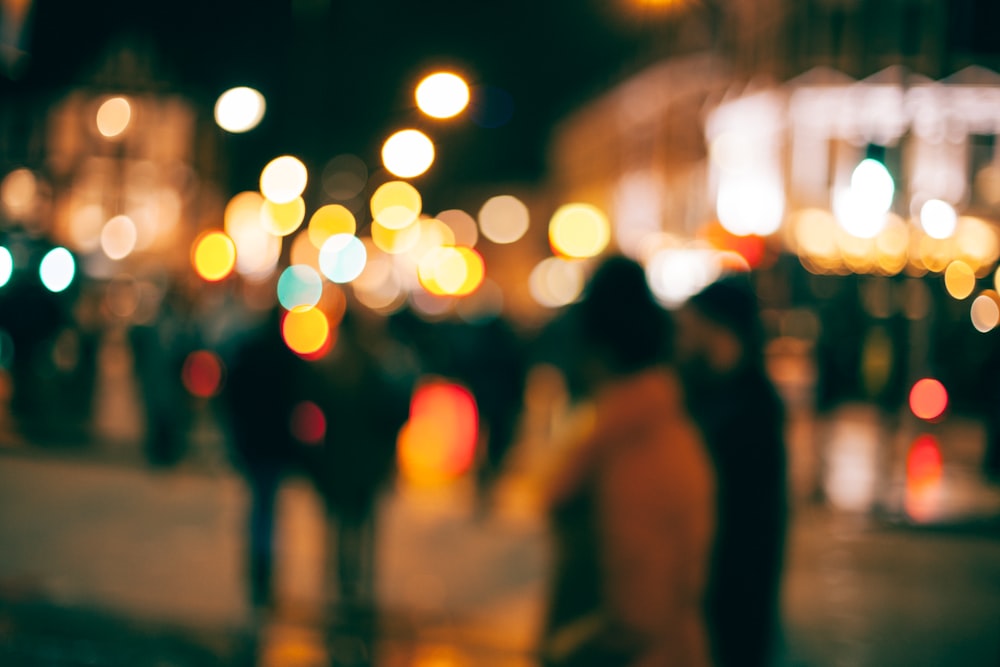 An out-of-focus look at people walking outside in a town at night with with blurs of dotted light all around
