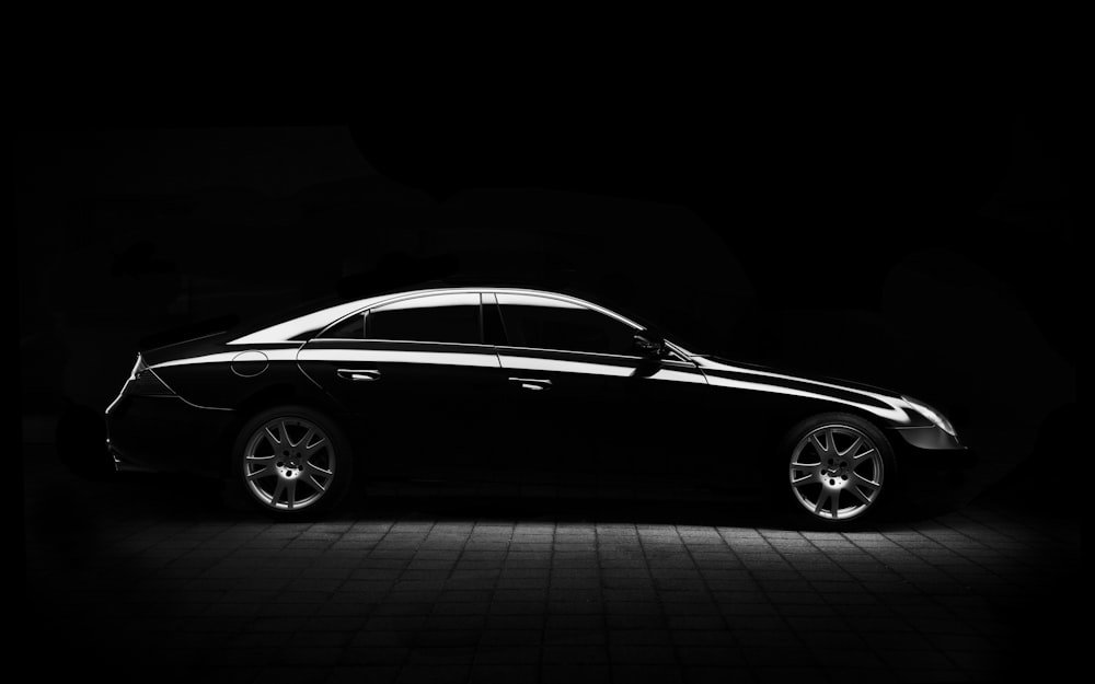 Black and white shot of black Mercedes-Benz saloon car on pavement at night