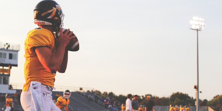 man holding brown football ball