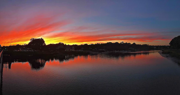 A serene Amazon river at sunset with vibrant orange and purple hues reflecting on the water.