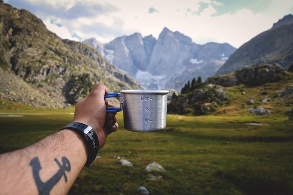 persona sosteniendo un vaso de plástico azul y blanco