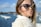 woman wearing blue-framed cat-eye sunglasses with body of water background