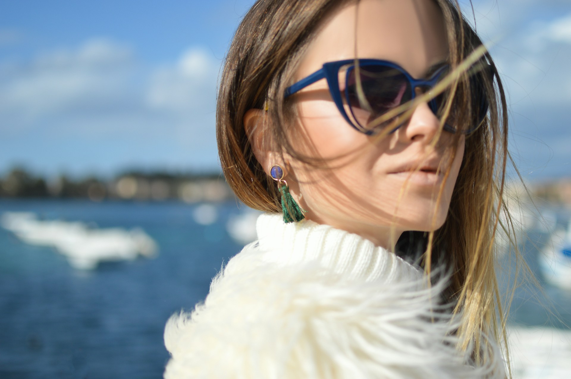 woman wearing blue-framed cat-eye sunglasses with body of water background