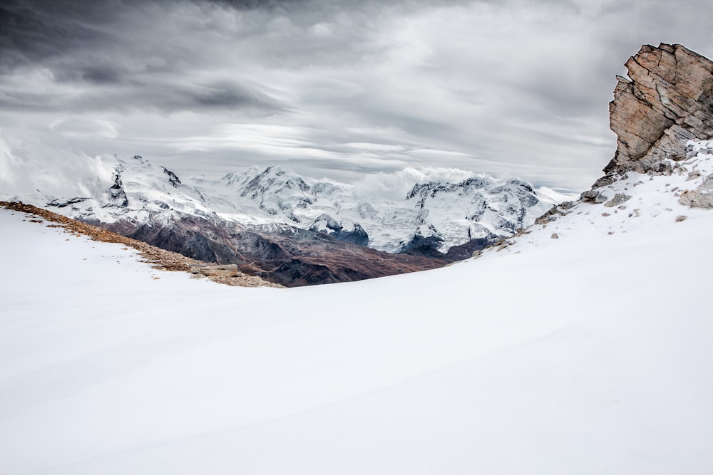 Montanha marrom coberta de neve sob céu nublado escuro