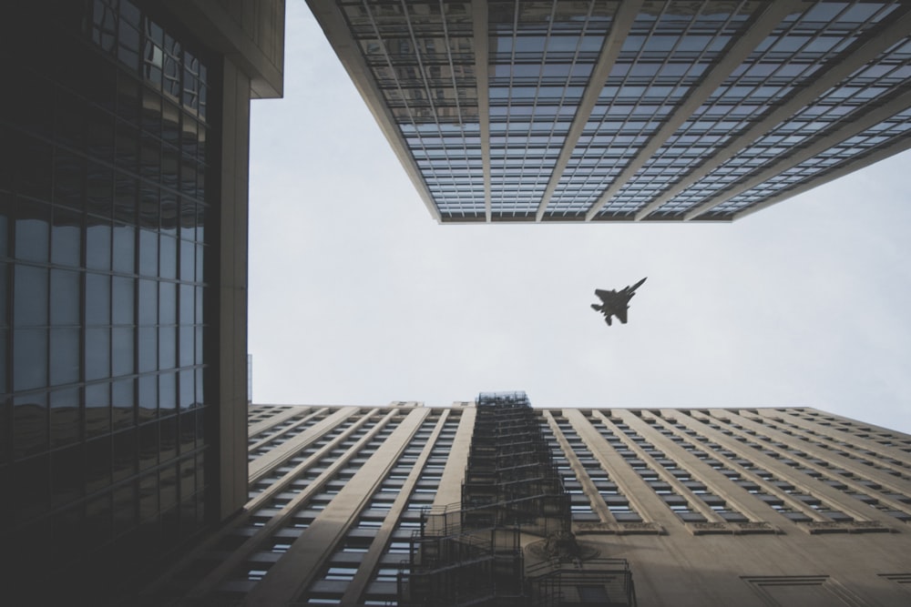 worm's view photo of fighter jet flying above building