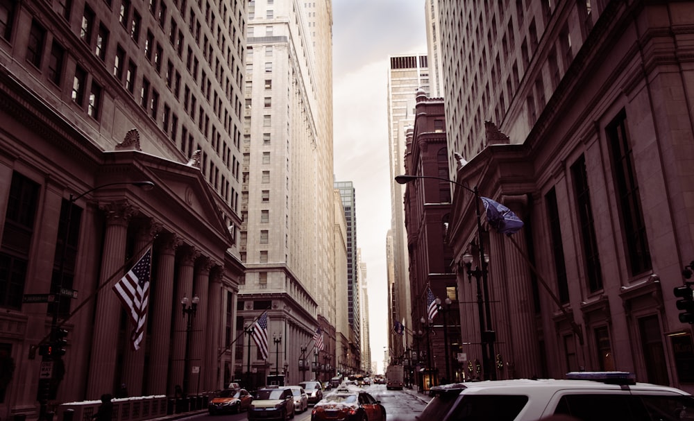 vehicles on concrete road between high buildings under white sky at daytime