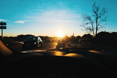 A scenic view of a road trip with a rental car against a sunset backdrop.