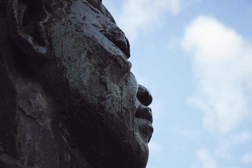 person statue under white clouds closeup photography
