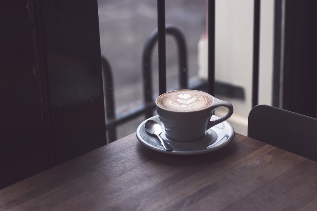 cappuccino in white teacup on brown wooden surface