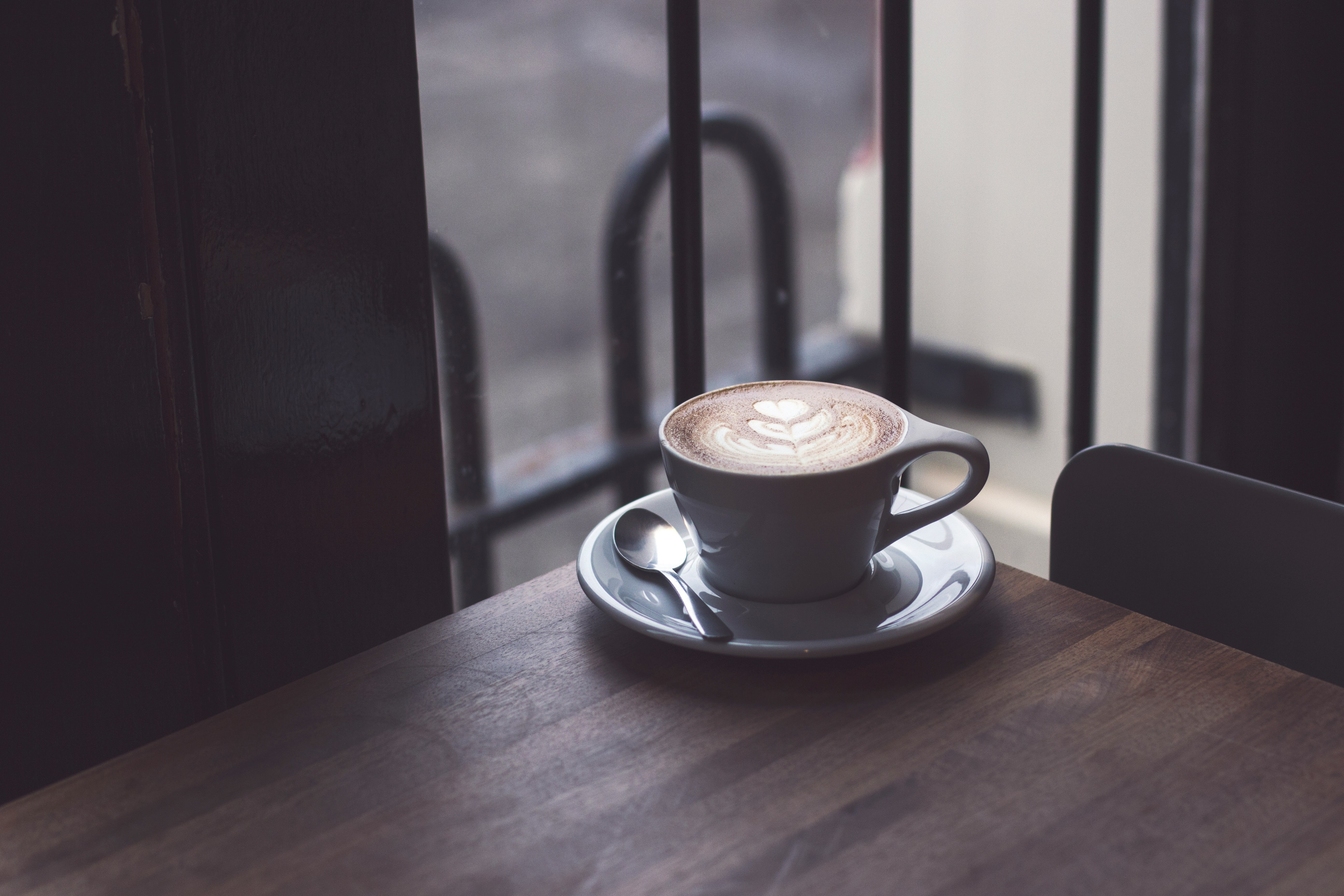 cappuccino in white teacup on brown wooden surface