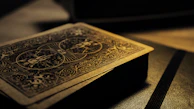 The back of a single tarot card showing the elegant foil design, shimmering softly in natural light.