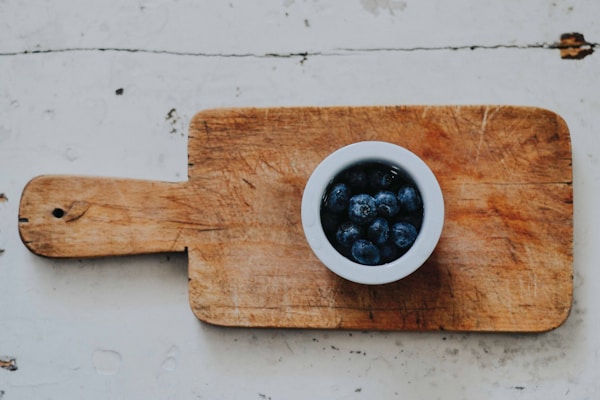 Blueberries on white saucer on chopping board