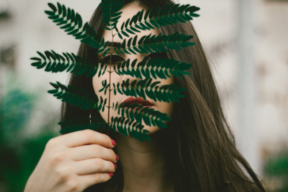 girl holding leaf outdoor during daytime