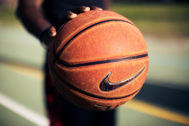 Close-up of a handball with the school’s clover logo resting on the court.