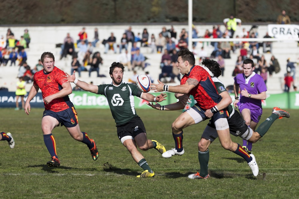 five men playing rugby during daytime