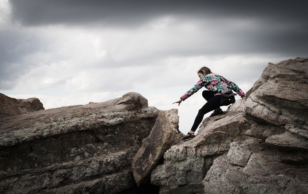 woman climbing on rocks during daytime photography