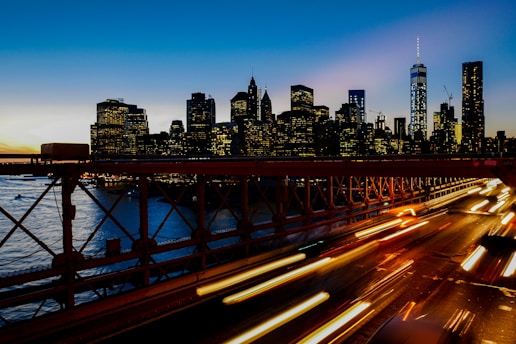 A long-exposure shot of light trails on the freeway with the New York city skyline at the back