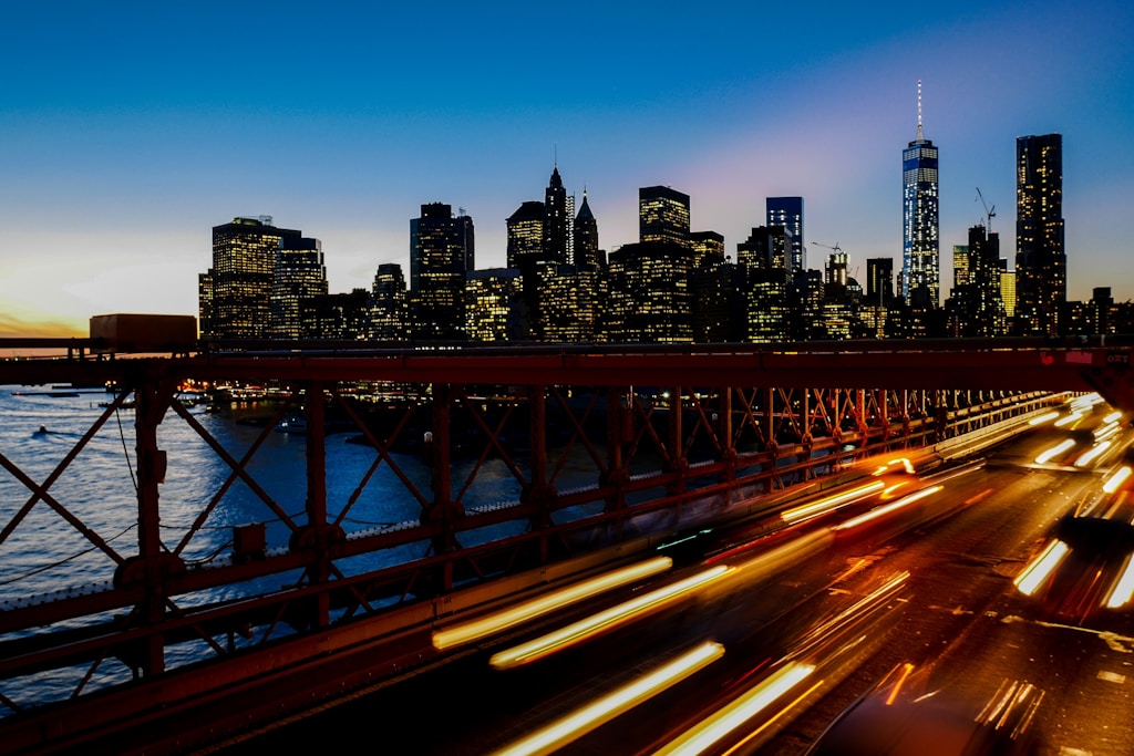 A long-exposure shot of light trails on the freeway with the New York city skyline at the back