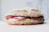 Close-up of a fresh sourdough sandwich with crisp greens and melted cheese on rustic wooden table.