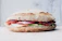 Close-up of a delicious milanesa torta with fresh lettuce and tomato on a rustic wooden table.