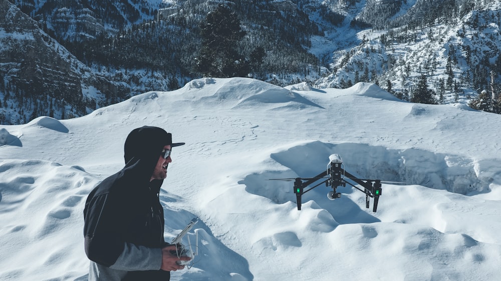 uomo in giacca nera con cappuccio che controlla il drone nero