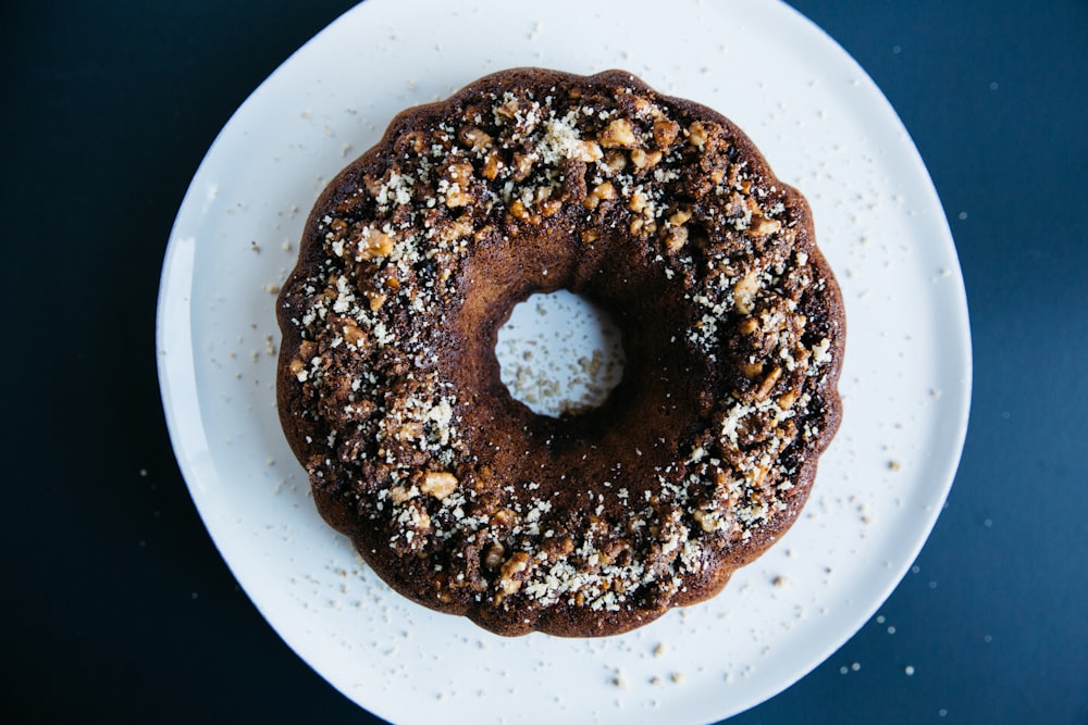 peanut sprinkled doughnut placed on round white ceramic saucer