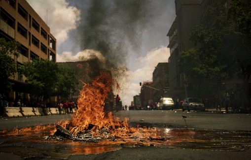 fire burning on the road with high rise buildings during daytime photography