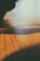 Close-up of a wooden ambient lamp casting soft light on a textured earth-toned surface.