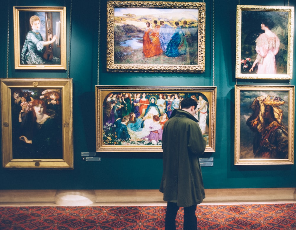 person standing near six paintings inside gallery