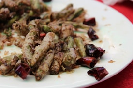 A plate of stir-fried green beans and dried red chilies, seasoned and served as a dish.