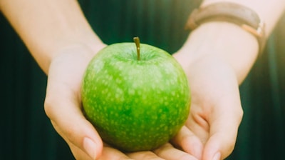 person holding green apple