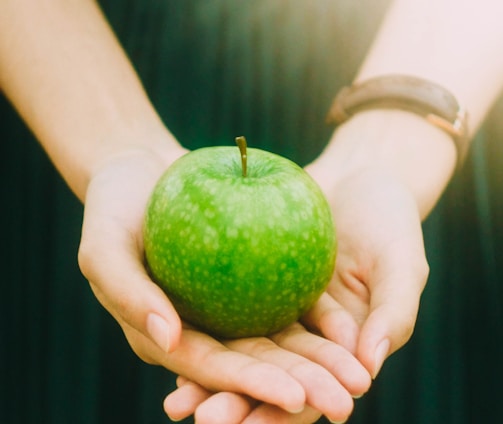 person holding green apple