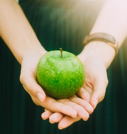 person holding green apple