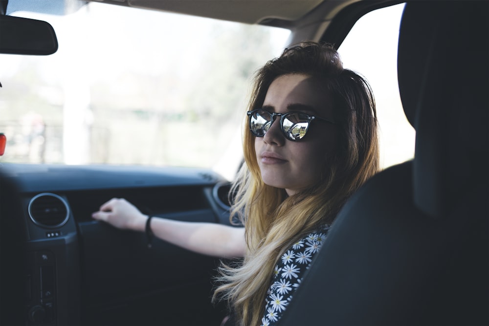 woman in black and white floral dress inside a grey vehicel