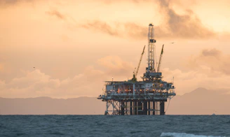 A sturdy offshore oil rig silhouetted against a deep blue sky at dusk.