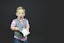 boy wearing gray vest and pink dress shirt holding book