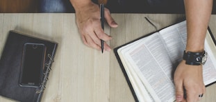 person holding bible with pen