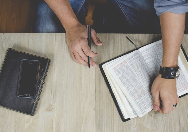 person holding bible with pen