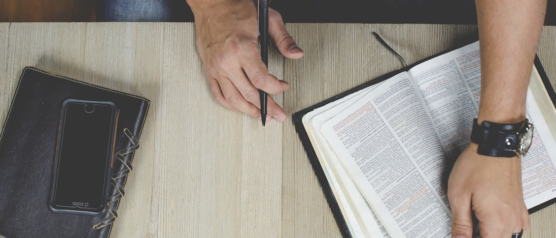 person holding bible with pen