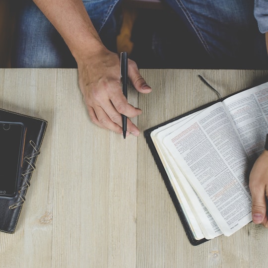 person holding bible with pen