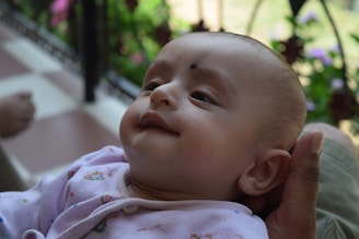 A soft pastel illustration of a baby holding a phone with a gentle smile.