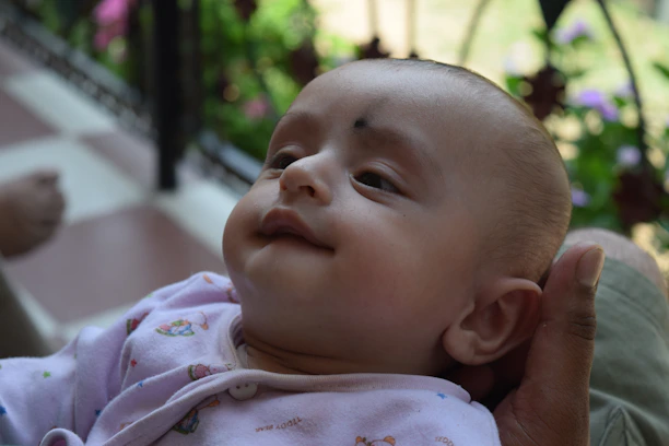 A happy parent gently holding their baby wearing a Cubcare onesie in a sunlit nursery.