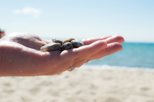 Close-up of hands gently holding smooth sea stones, symbolizing grounding and calm.