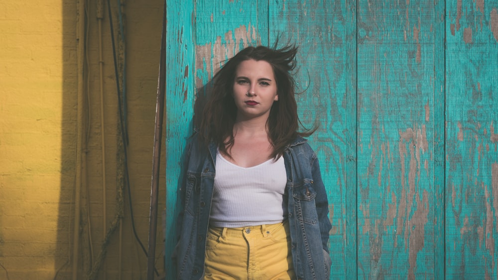 woman in white top leaning on wall